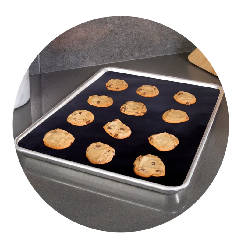 Fresh cookies baking on a PTFE non-stick baking liner in a home kitchen