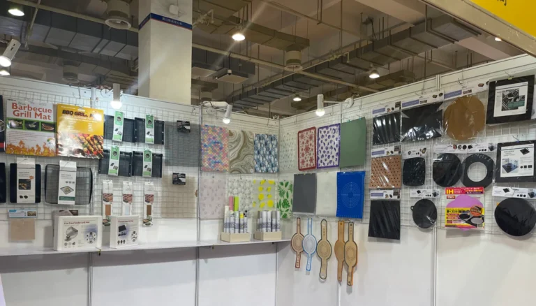 Tianyu Synthetic's exhibition booth at a trade show, showcasing the full range of our PTFE grill mats, PTFE baking liners, silicone mat, EVA shelf liners in distinctive branded packaging.