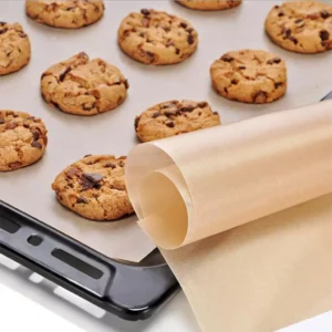 PTFE Baking Mat in classic brown culinary color, rolled and placed on a commercial oven tray with baked cookies for bulk B2B wholesale.