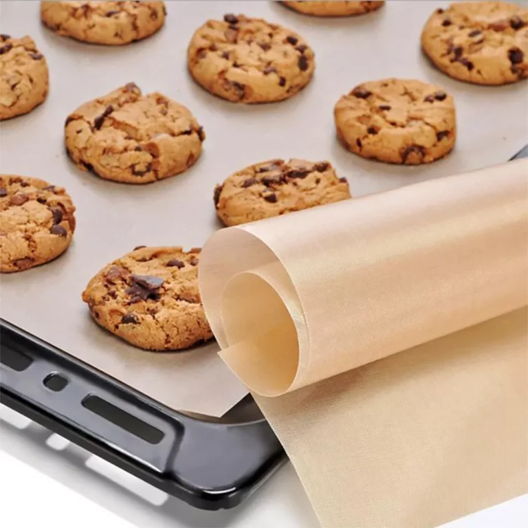 PTFE Baking Mat in classic brown culinary color, rolled and placed on a commercial oven tray with baked cookies for bulk B2B wholesale.
